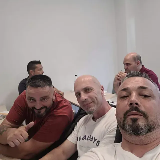Un grupo de hombres están sentados en una mesa y uno de ellos lleva una camisa que dice siempre