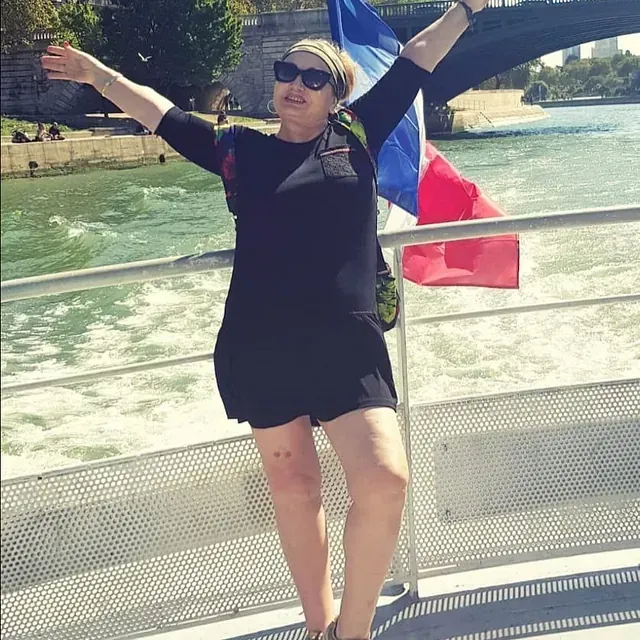 Una mujer parada en un bote con los brazos extendidos