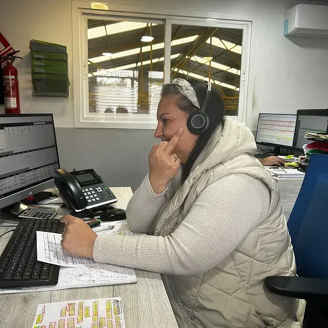 Una mujer con auriculares está sentada en un escritorio frente a una computadora.