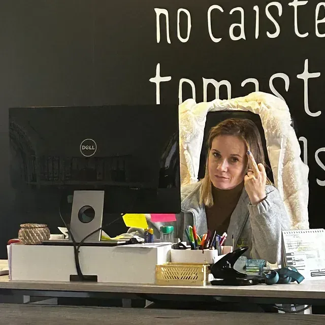 Una mujer se sienta en un escritorio frente a una computadora Dell.