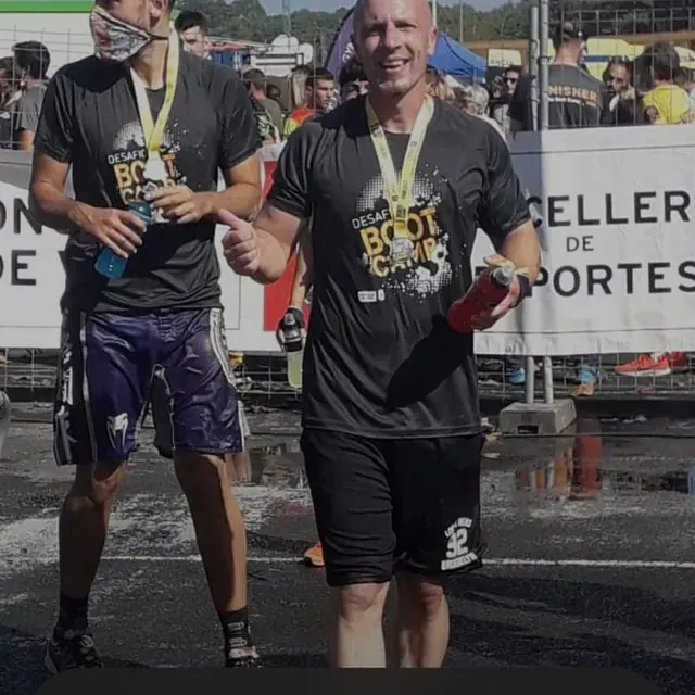 Un hombre que viste una camiseta de entrenamiento militar está junto a otro hombre.