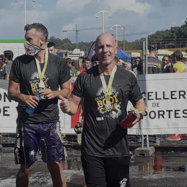 Dos hombres con camisetas de entrenamiento militar caminan frente a un cartel que dice 