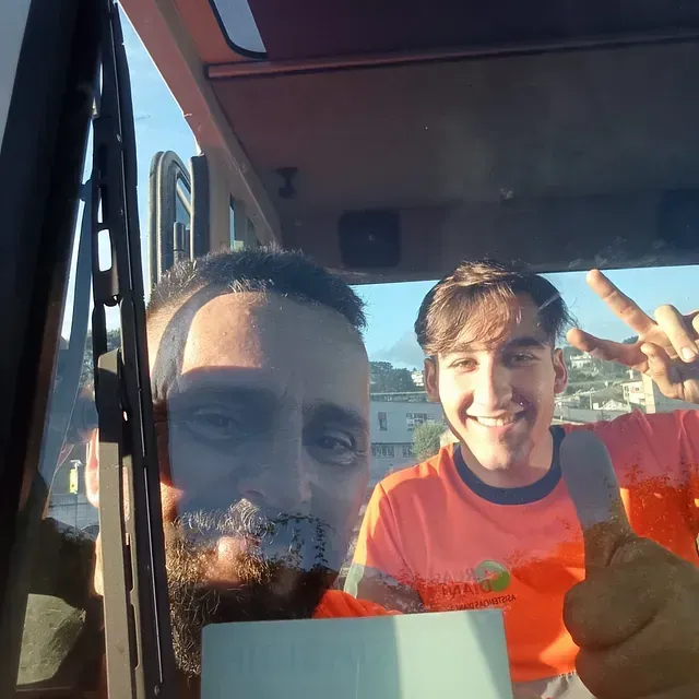Un hombre con una camisa naranja está haciendo un gesto de aprobación con el pulgar hacia arriba.