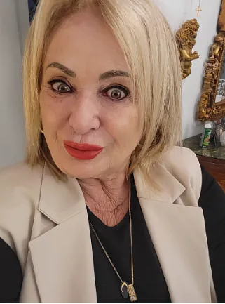 Una mujer con una chaqueta blanca y una camisa negra se está tomando un selfie.