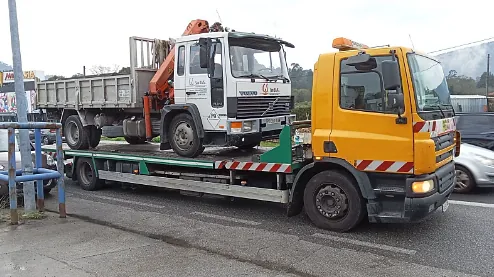 Una grúa amarilla transporta un camión blanco