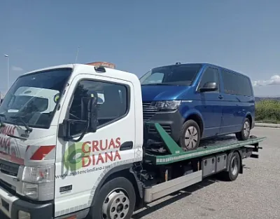 Una grúa con una camioneta azul en la parte trasera.