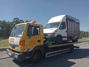 Una grúa amarilla transporta una camioneta blanca y un camión rojo.