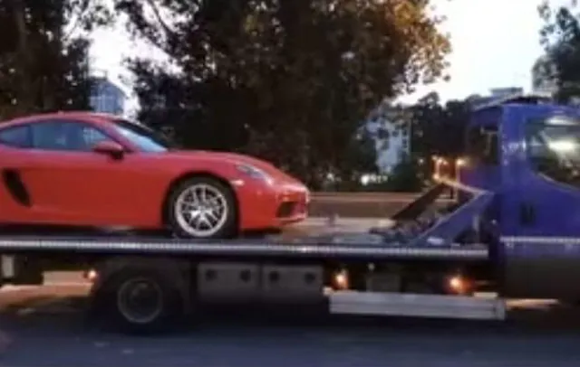 Un coche deportivo rojo está siendo remolcado por una grúa.