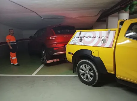 Una grúa amarilla está estacionada al lado de un auto rojo