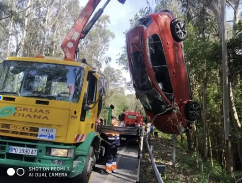 Un coche está siendo levantado por una grúa desde el suelo.
