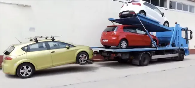 Un coche amarillo está siendo remolcado por una grúa azul.