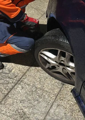 Una persona está cambiando una llanta en un auto azul.