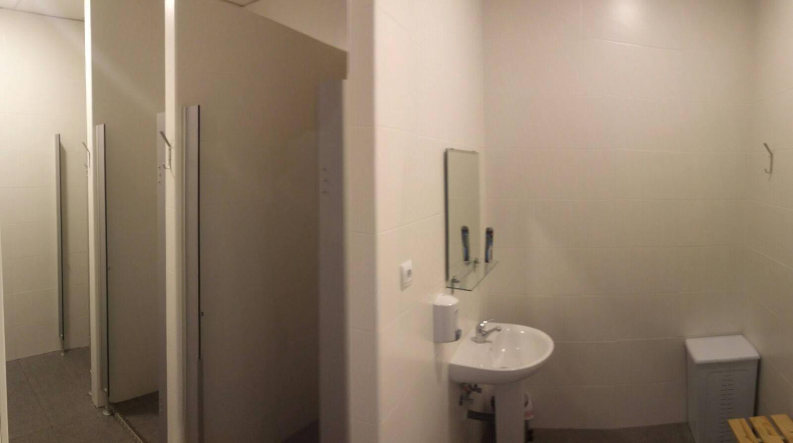 Un baño con lavabo, espejo y un banco de madera.