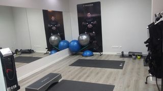 Un gimnasio con muchos equipos de ejercicio y un espejo grande.