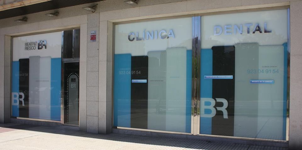 Una clínica dental con un cartel azul y blanco en las ventanas.