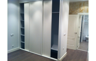 Un armario con puertas correderas y estantes en una habitación.