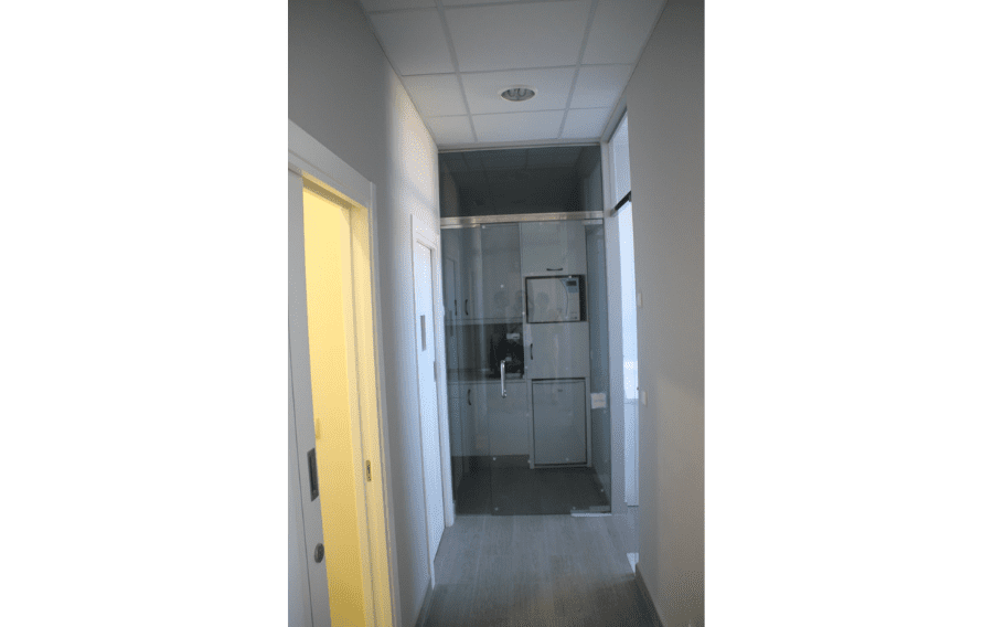 Un pasillo con una puerta corrediza de vidrio que conduce a un baño.