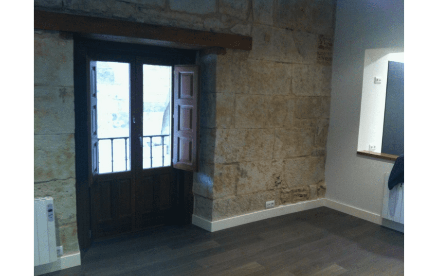 Una habitación vacía con una pared de piedra y una puerta de madera.