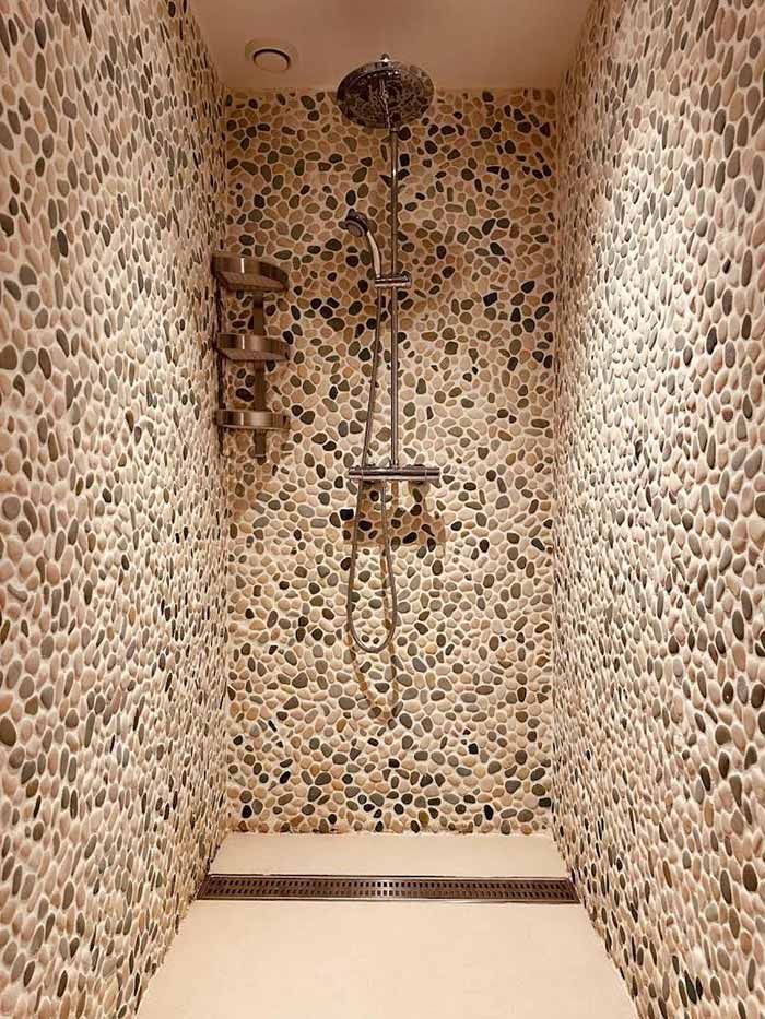 Una ducha con pared de piedra y cabezal de ducha.