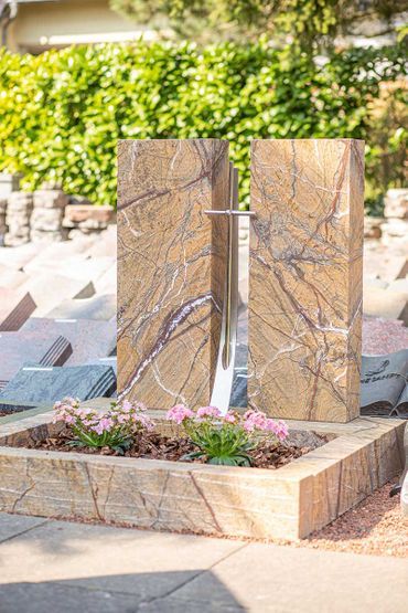 hellgrauer Grabstein, im Hintergrund sind weitere Grabsteine