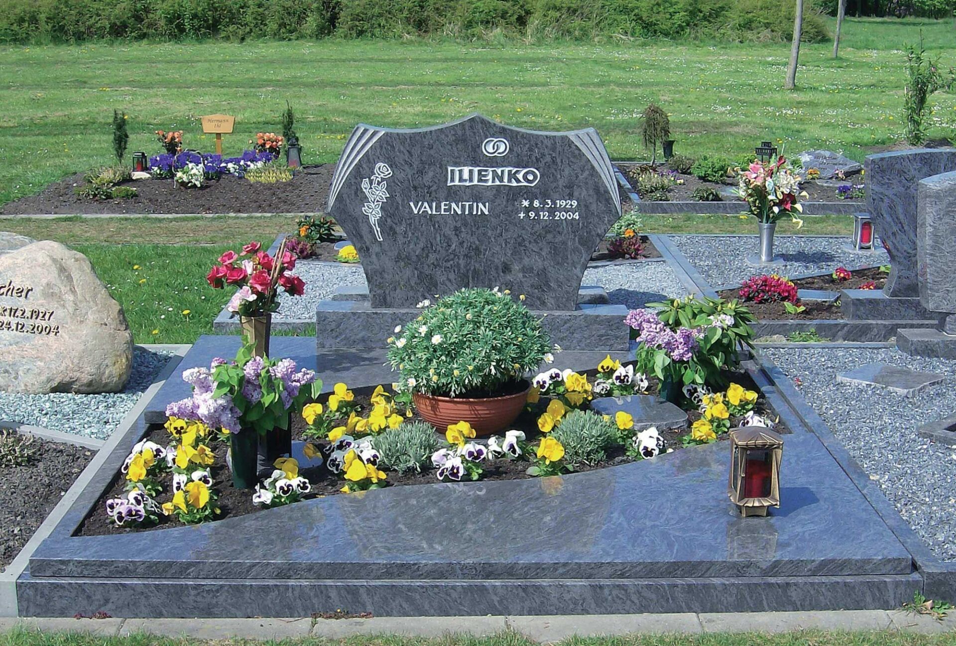 Grabstein mit Verzierung und Beschriftung; Grab mit Steineinfassung