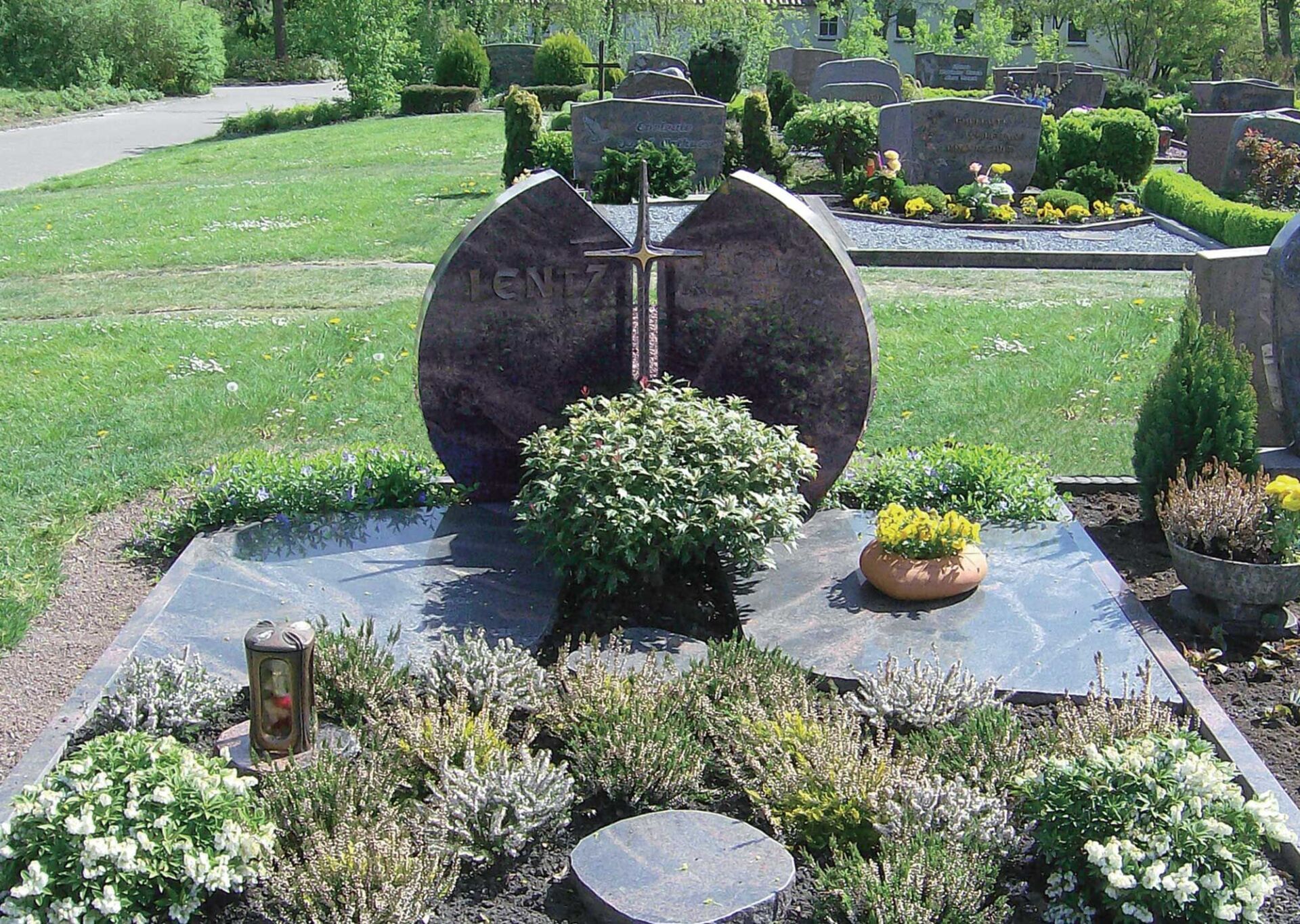 Kunstvoller Grabstein und Grab mit Steineinfassung