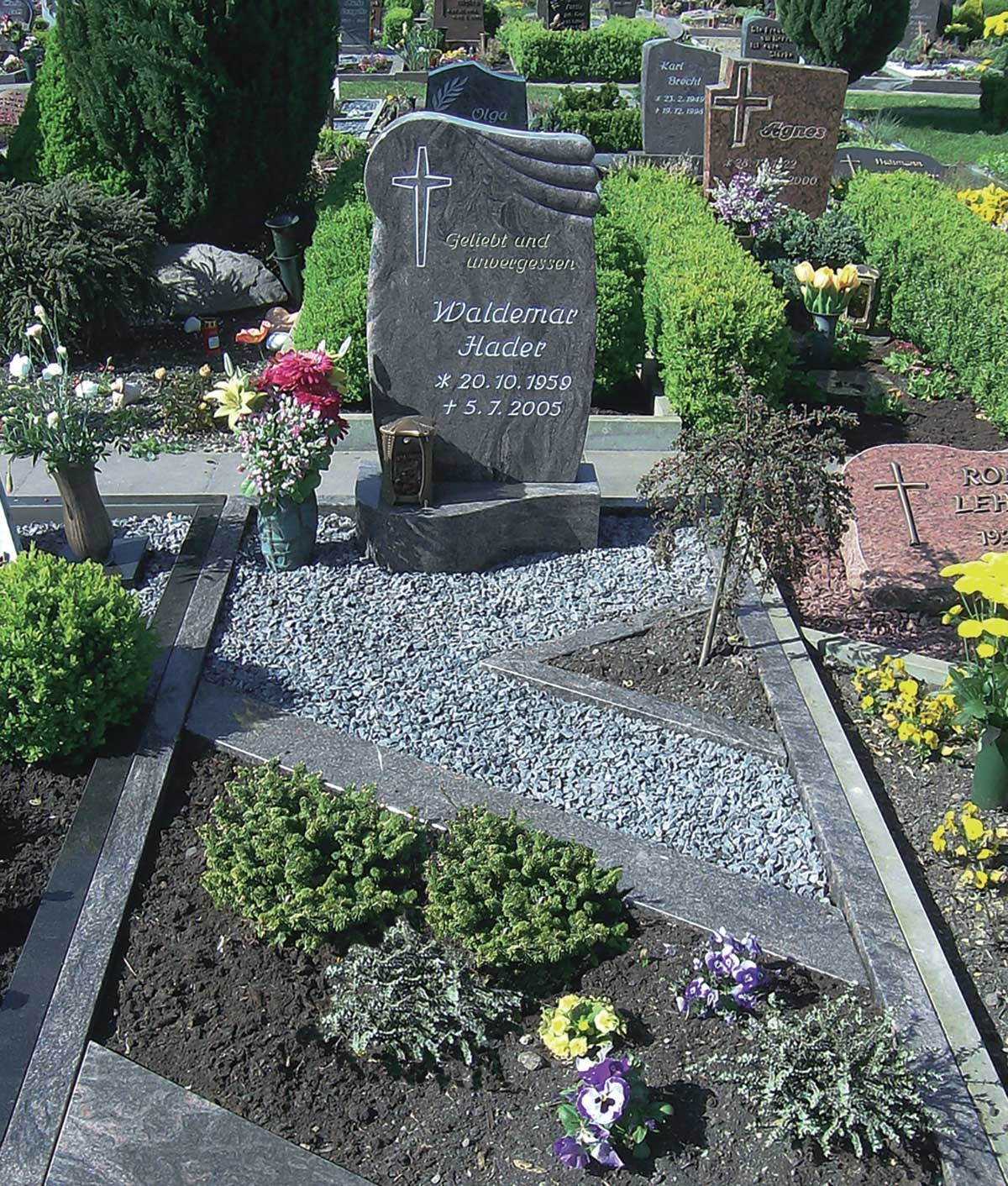 Grab mit beschriftetem und verzierten Grabstein, Kiesfläche und Steinfläche