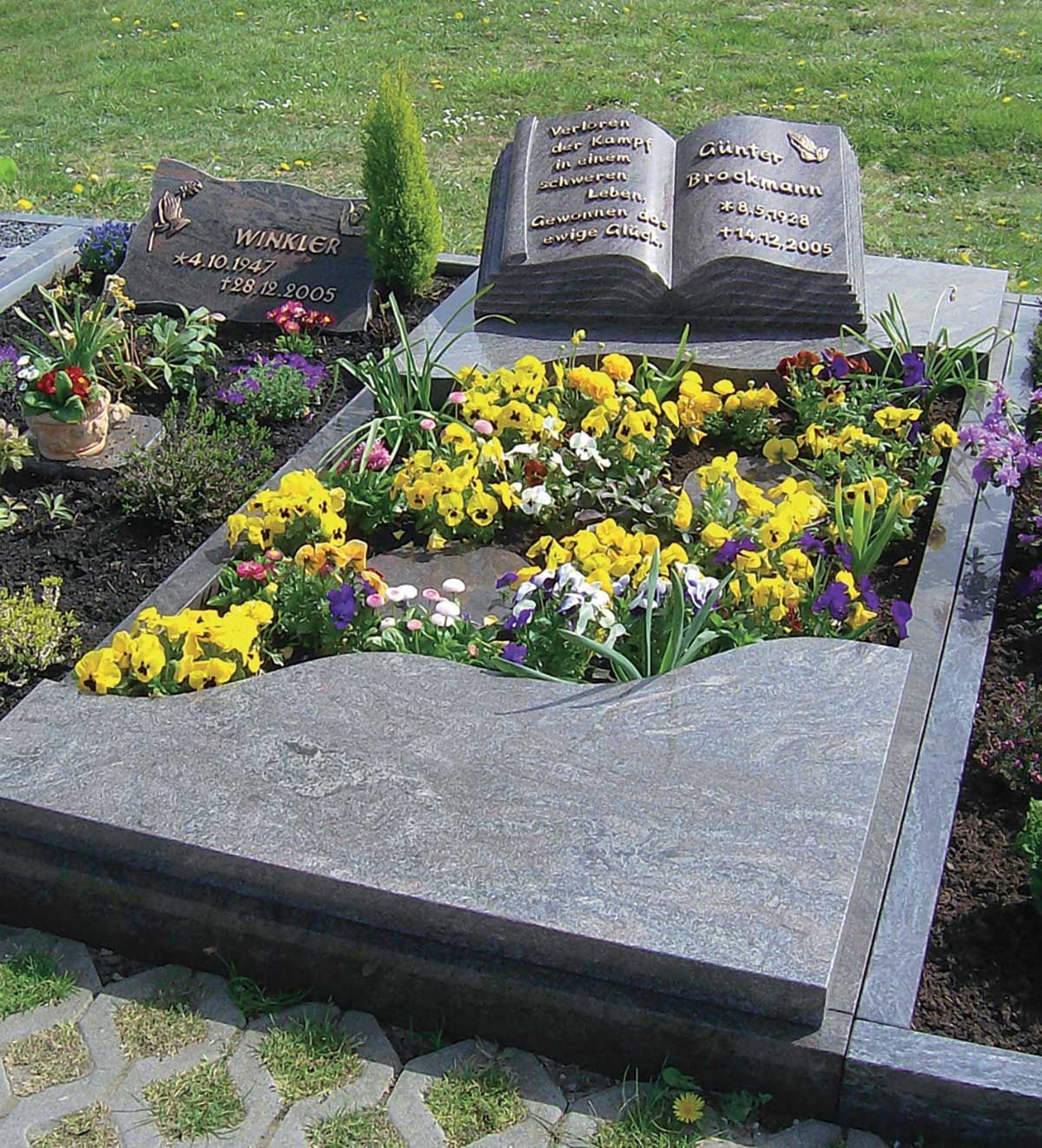 Grab mit buchförmigem Grabstein, Steinplatte und Blumenschmuck