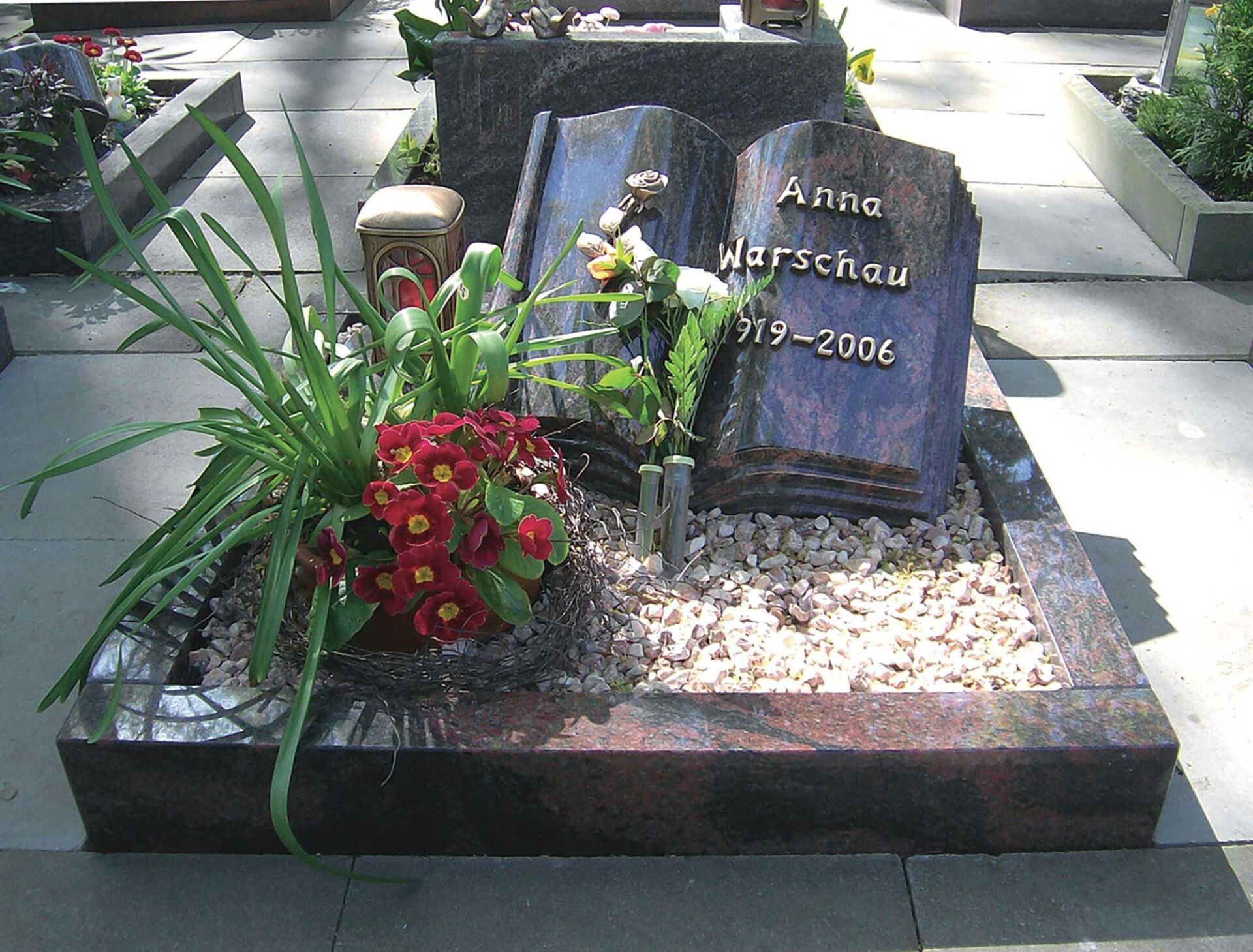 Grab mit Blumenschmuck und Grabstein in Buchform