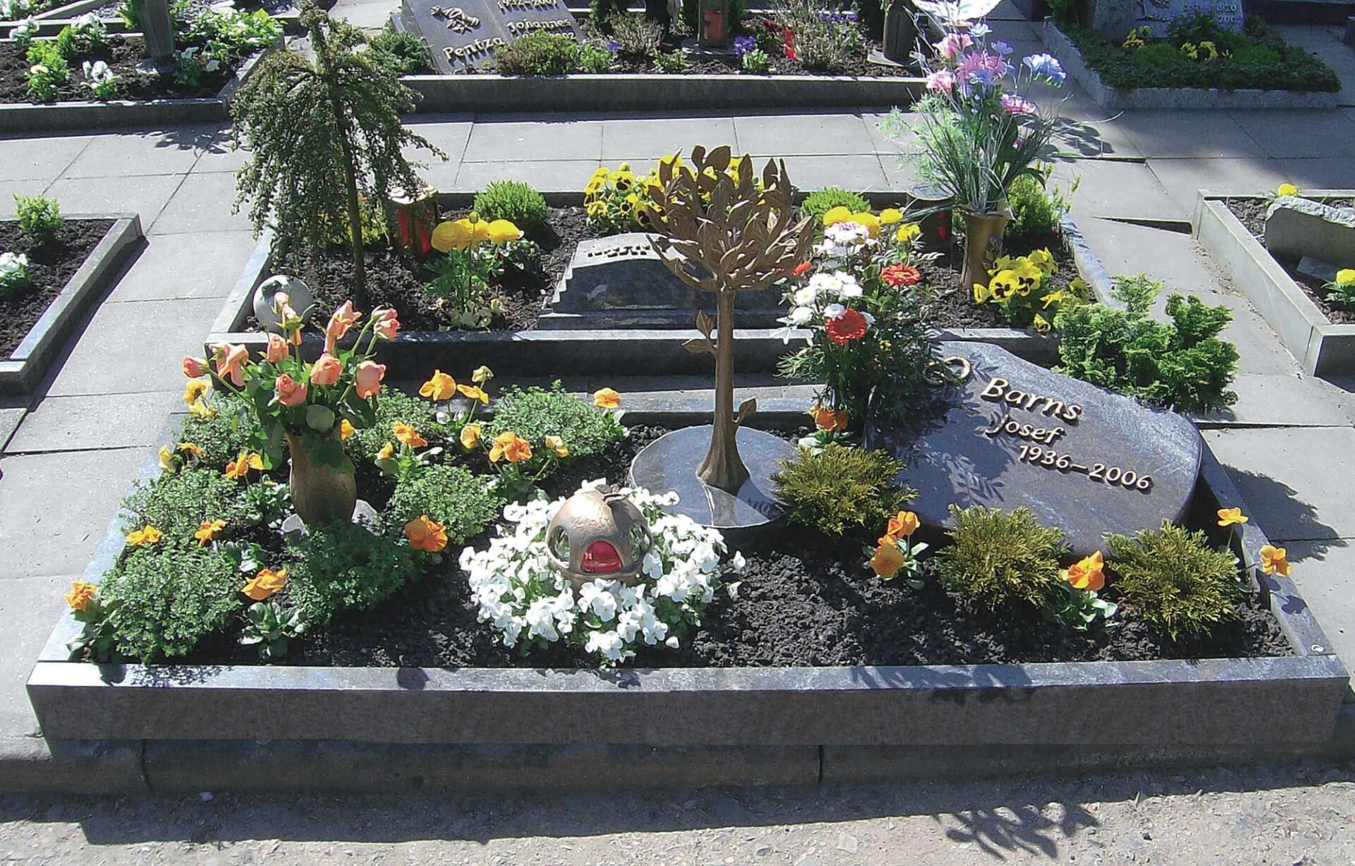 Grab mit kleinem liegenden Grabstein, Pflanzen und Eisenschmuck