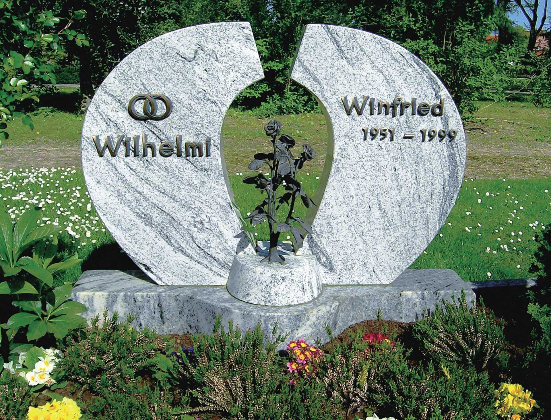 abgerundeter Grabstein mit Beschriftung und Aussparung in der Mitte