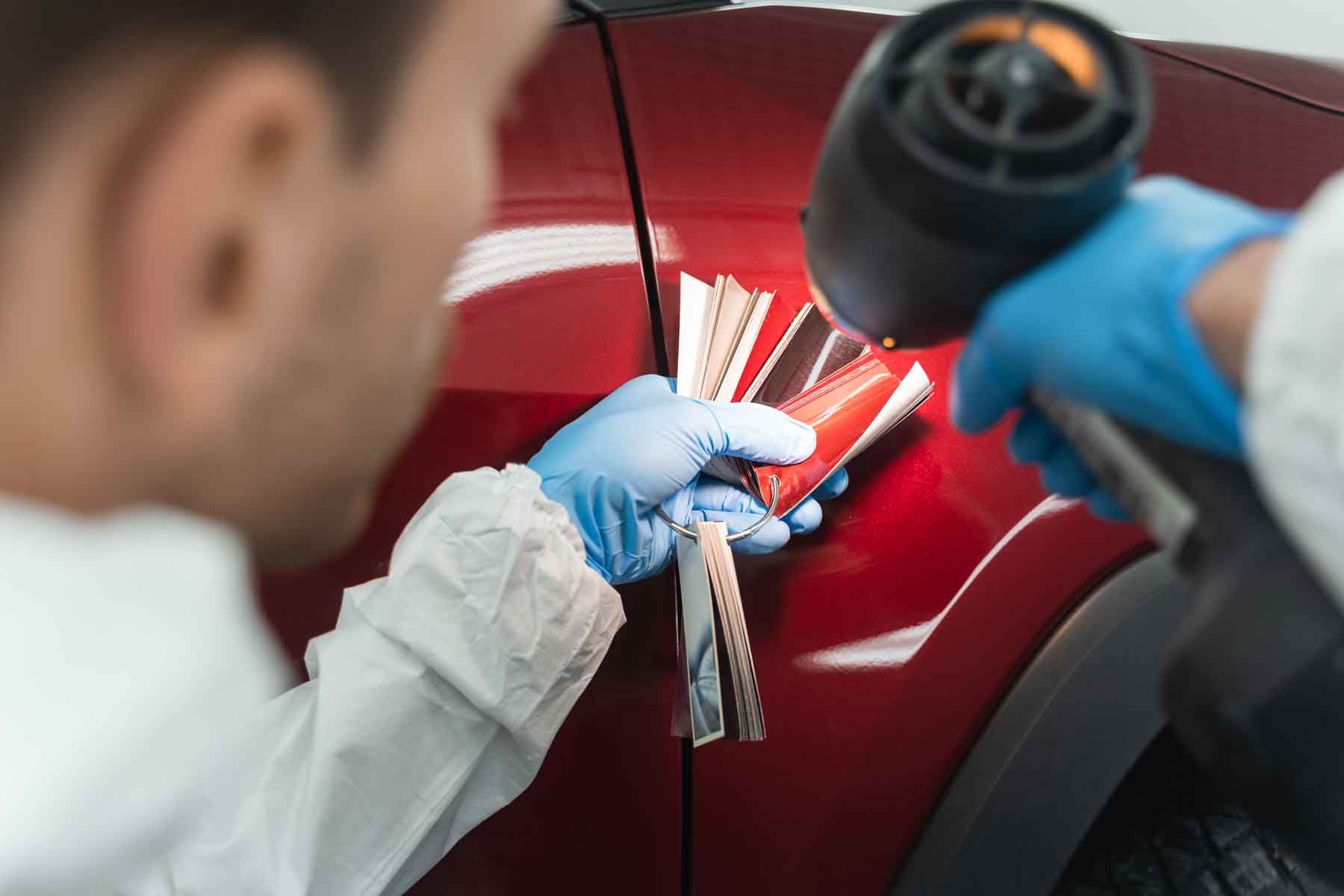 Un technicien utilise un nuancier avec une lampe afin de voir la couleur adaptée au véchicule