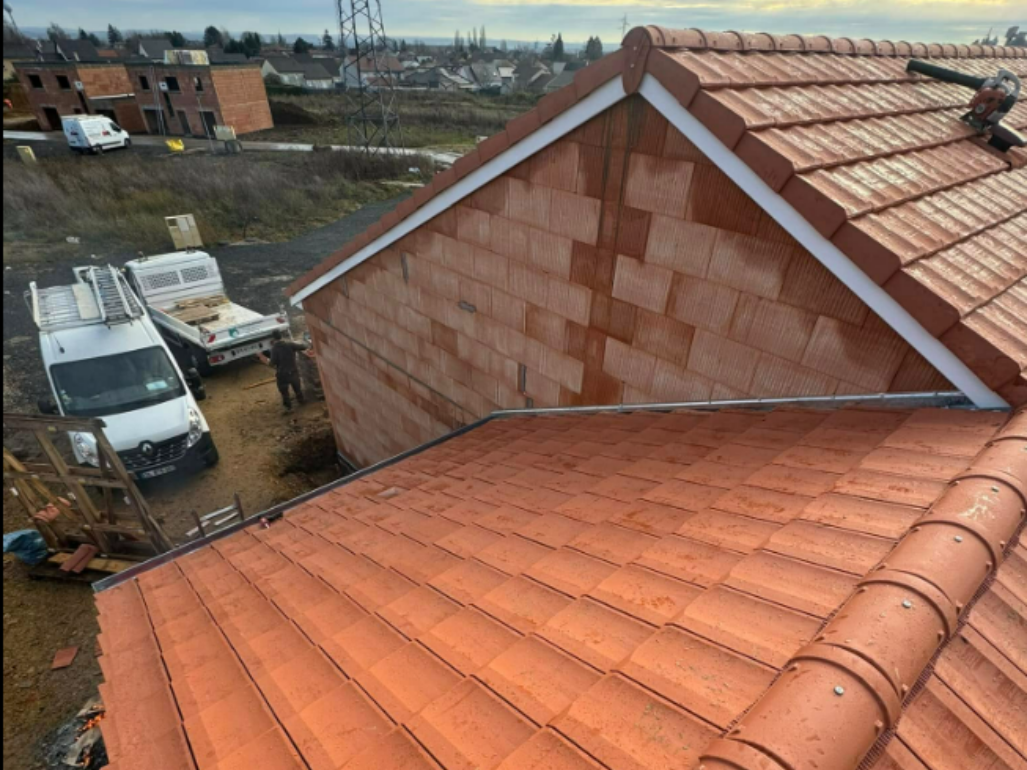 Toit de tuiles rouges sur un bâtiment en construction, avec des camions.