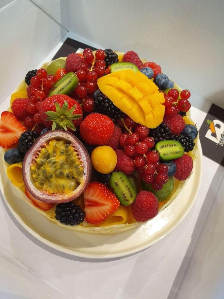 Gâteau aux fruits, garni de fraises, de kiwi, de mangue, de myrtilles et de fruit de la passion, sur une assiette blanche