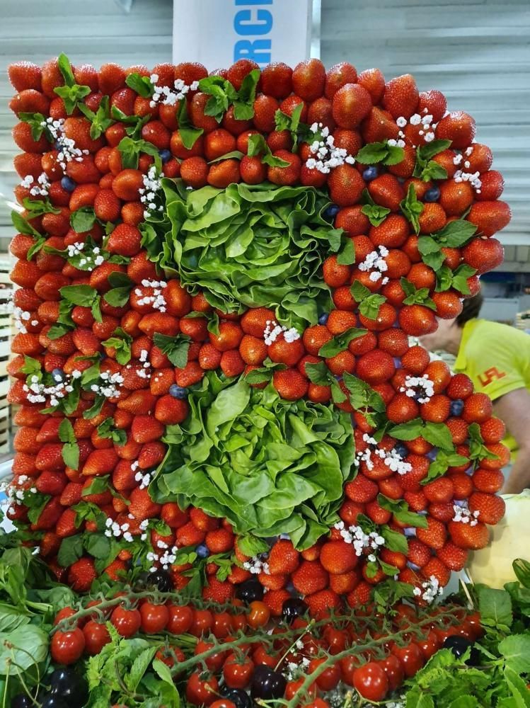 Présentoir à tomates avec deux centres feuillus verts sur un étal de marché