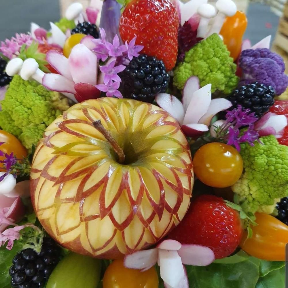 Composition centrale colorée de fruits sculptés avec une pomme, des fraises, des mûres, des raisins et des fleurs