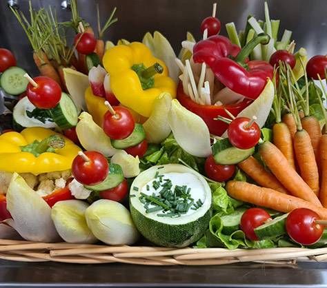 Un assortiment de légumes frais dans un panier, notamment des poivrons, des tomates, des carottes, des oignons et des concombres