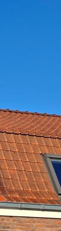 Bâtiment en briques au toit brun, jouxtant un poteau électrique.