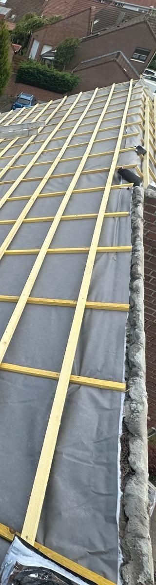 Une maison en briques au toit de tuiles rouges sous un ciel bleu.