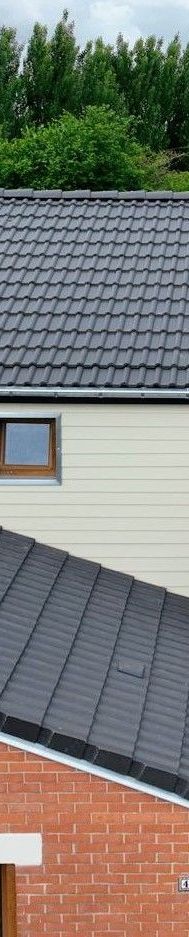 Bâtiment en briques avec un toit de tuiles. L'ombre d'un arbre recouvre partiellement le toit.