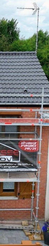 Une maison en briques au toit de tuiles rouges sous un ciel bleu.