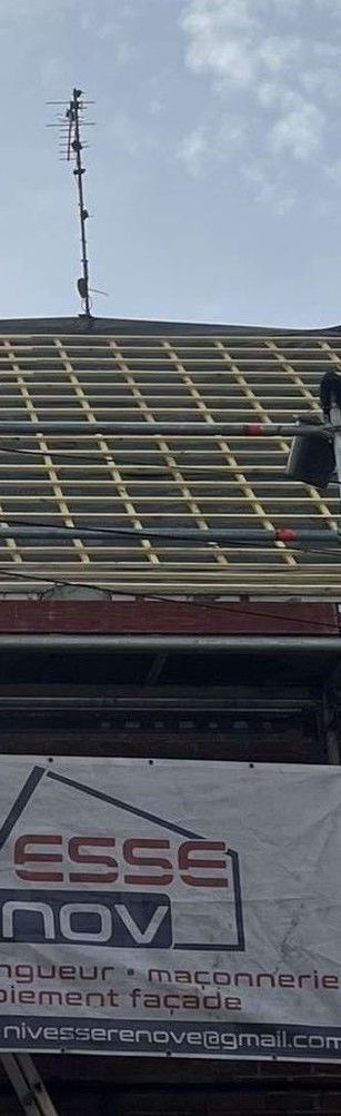 Une maison en briques au toit de tuiles rouges sous un ciel bleu.