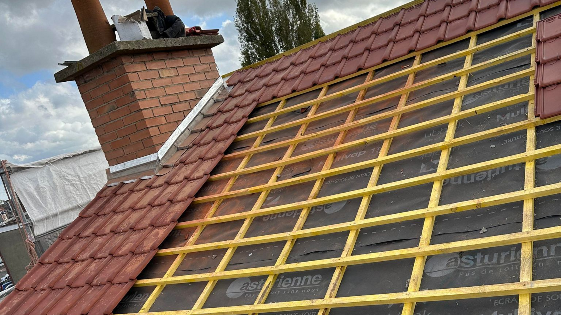 Toiture partiellement recouverte de tuiles rouges.