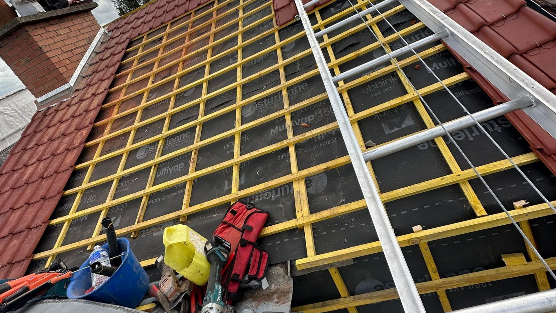 Toiture en construction avec charpente en bois apparente.