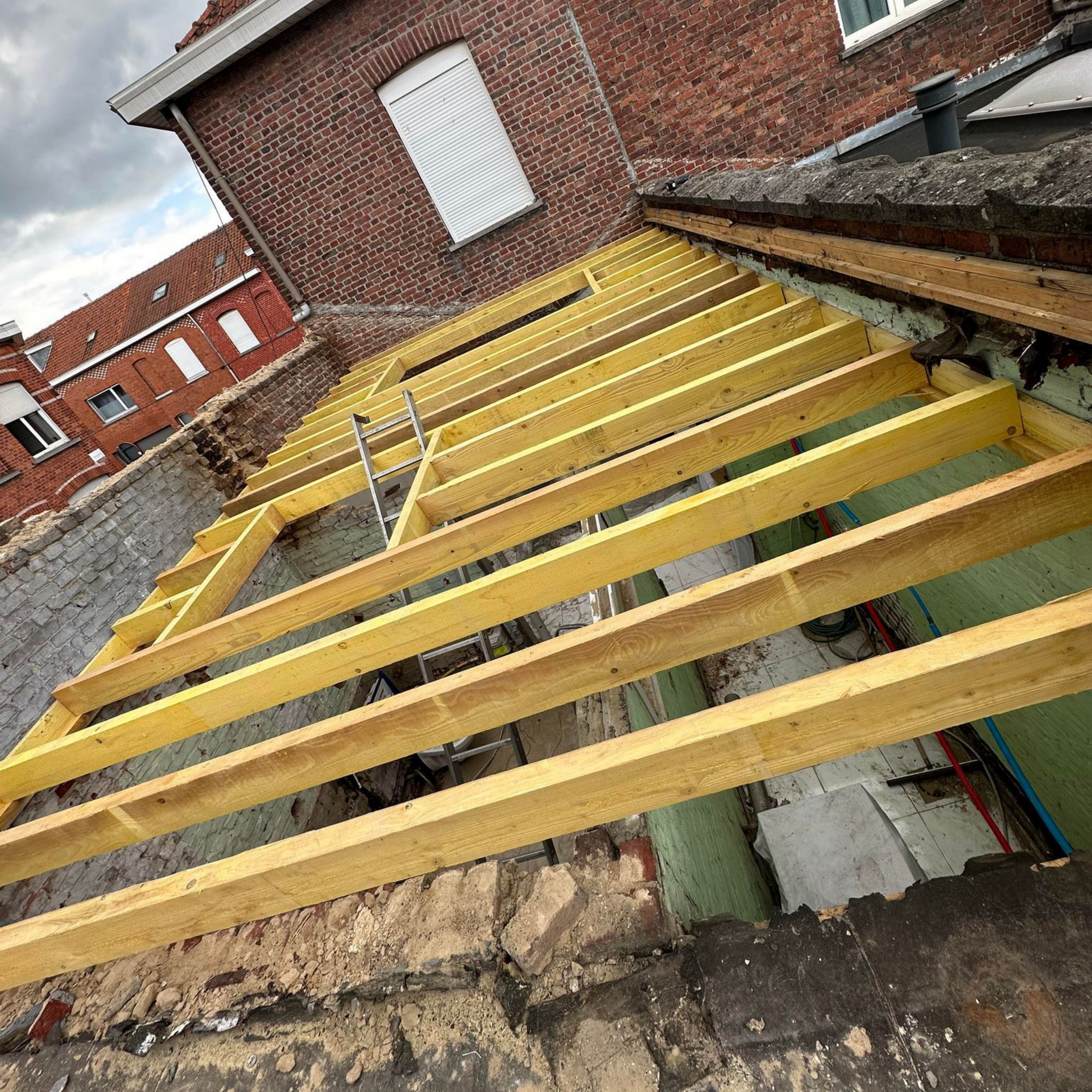 Construction de la charpente d'un toit sur un bâtiment en briques.
