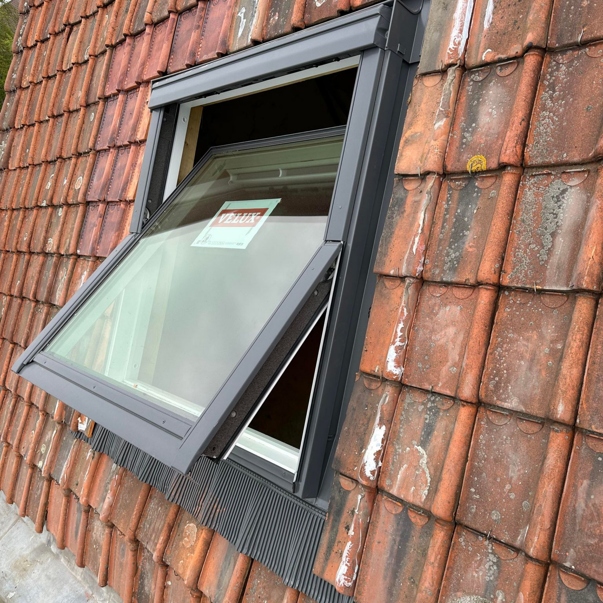 Puits de lumière ouvert dans un toit de tuiles rouges.