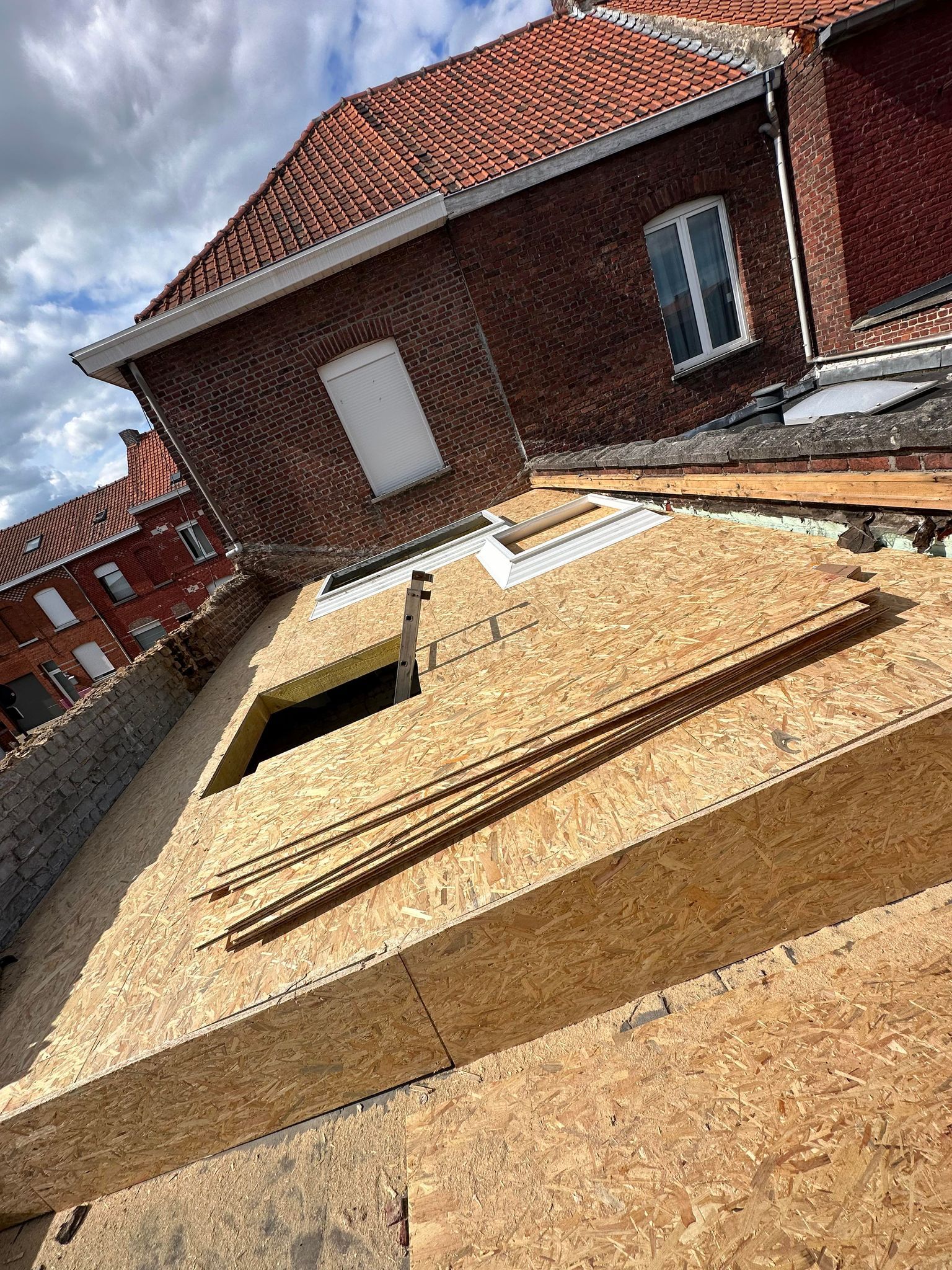 Toiture en construction, laissant apparaître des panneaux de bois.