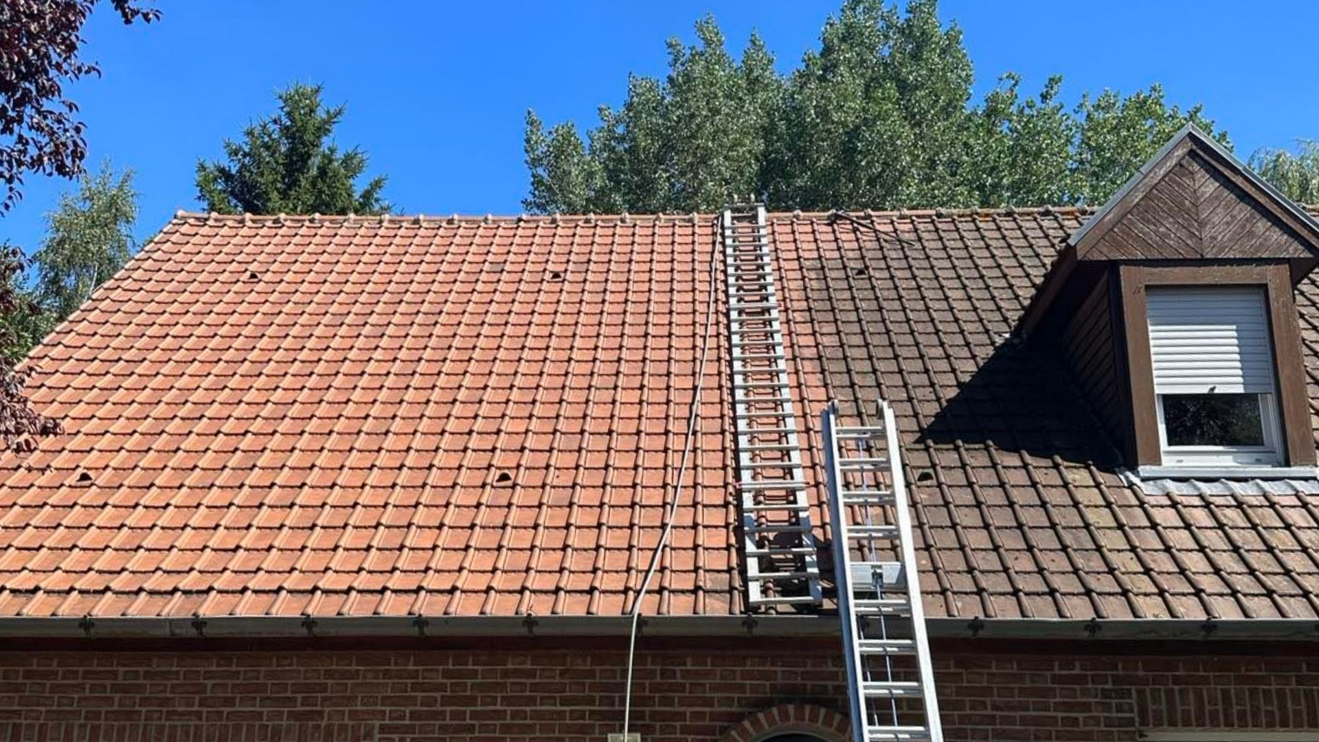 Échelle sur toit de tuiles rouges.