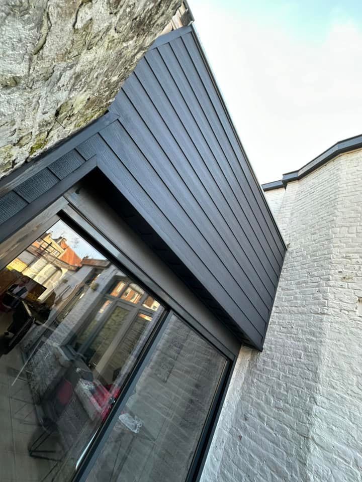 Un bardage noir surmonte une grande fenêtre d'un bâtiment.