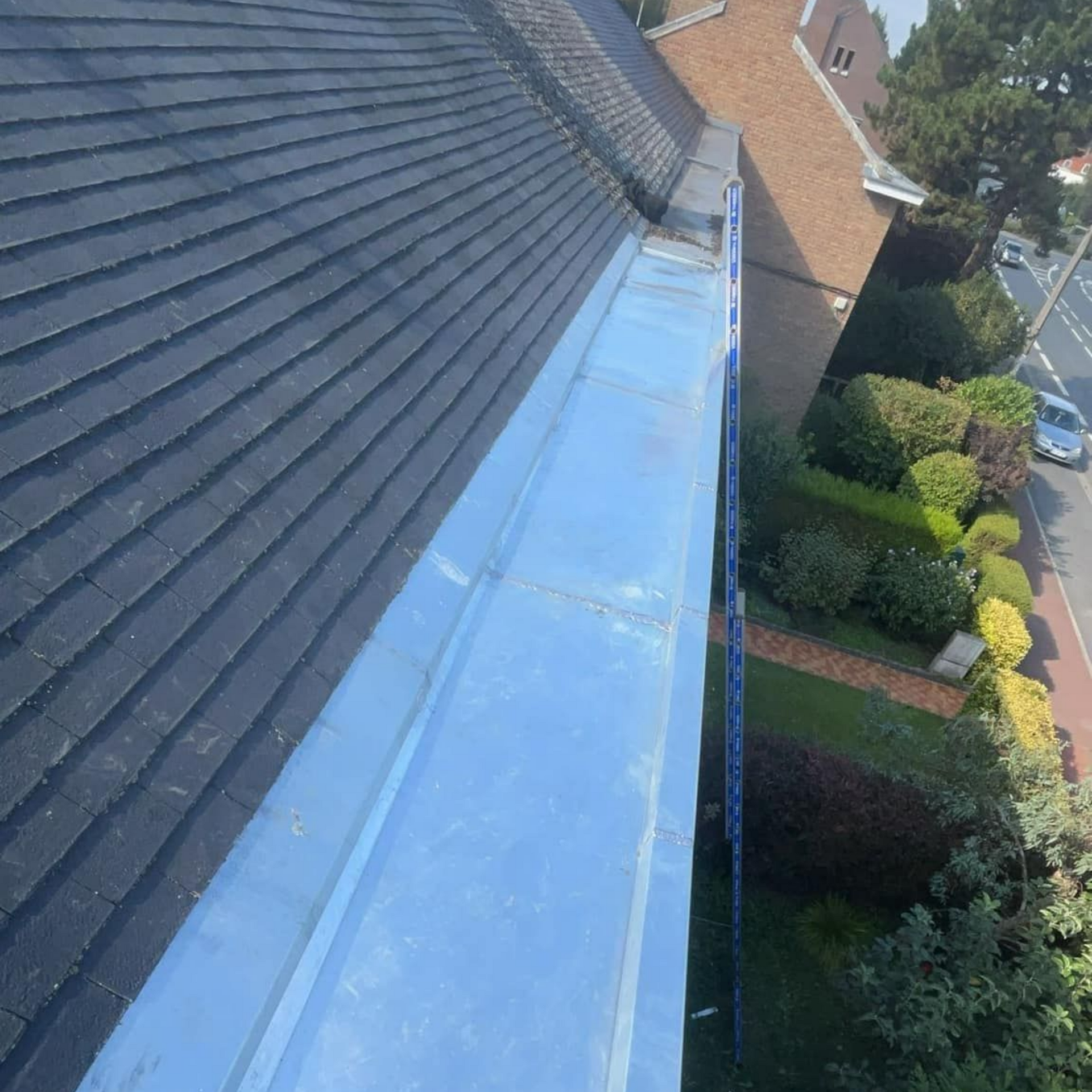 Vue aérienne d'un toit de tuiles noires avec une gouttière.